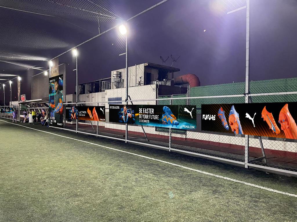 Forever Faster branded banner wall along the pitch at night